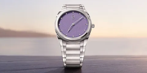 Montre avec cadran violet et bracelet en métal argenté devant un paysage flou.