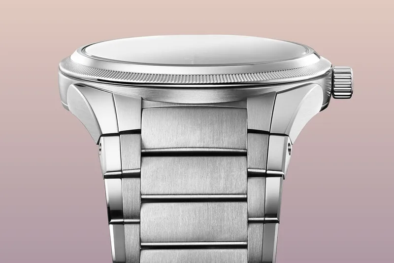 Montre en métal argenté avec bracelet en maillons et couronne à droite.