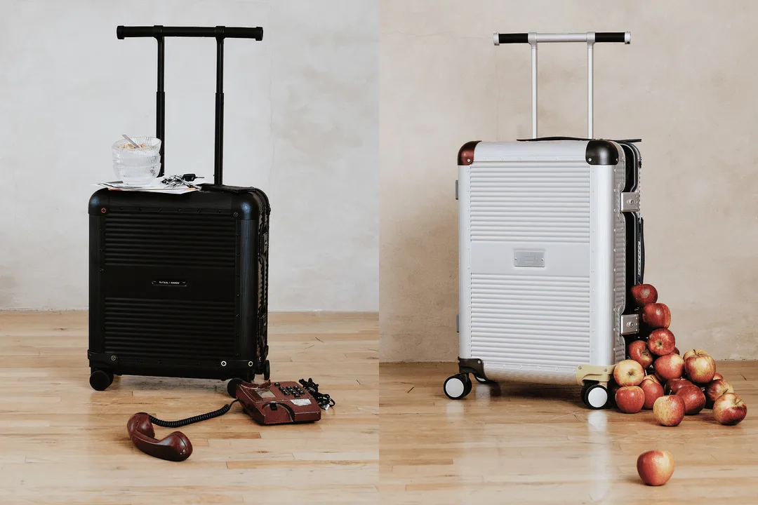Deux valises avec accessoires et pommes, sur fond de sol en bois.