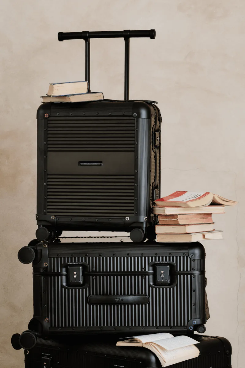 Valises empilées avec livres, poignée visible.
