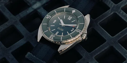 Montre-bracelet vintage à cadran vert sur un fond sombre texturé.