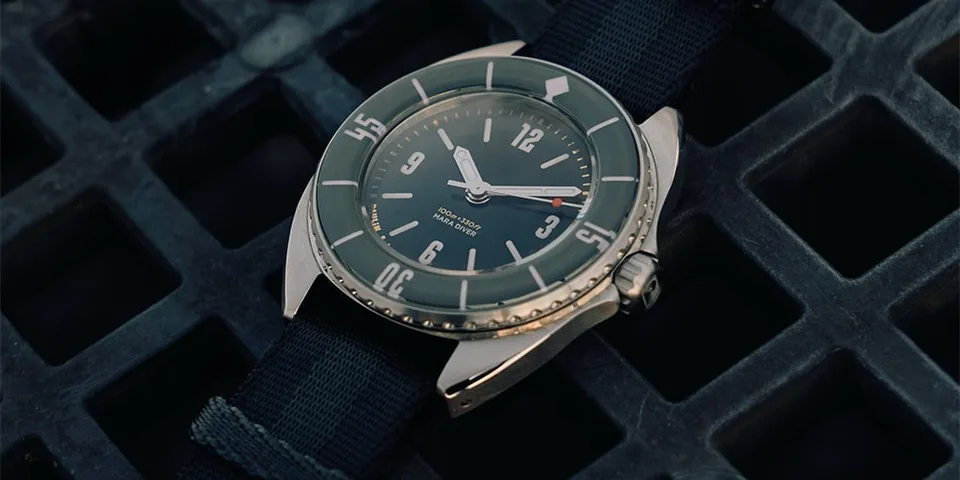 Montre-bracelet vintage à cadran vert sur un fond sombre texturé.