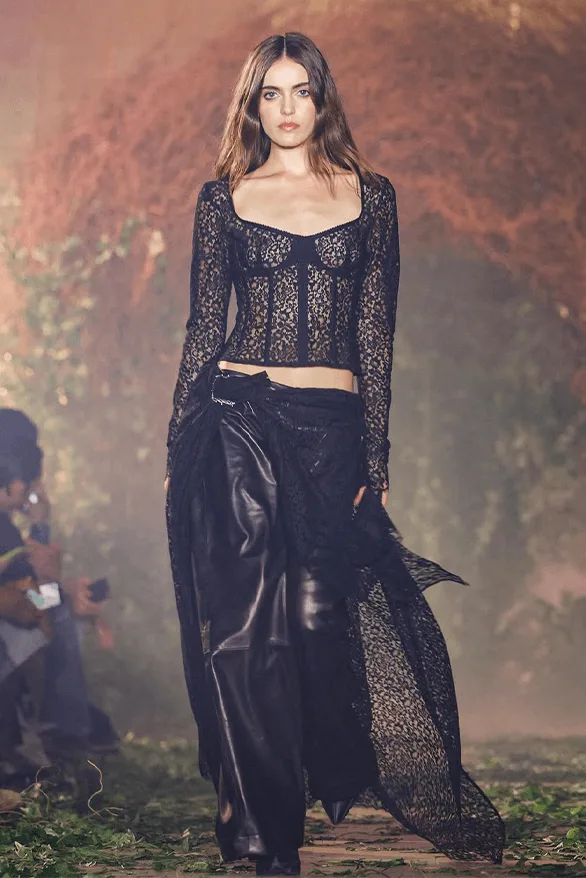 Femme défilant en tenue noire élégante lors d'un défilé de mode.