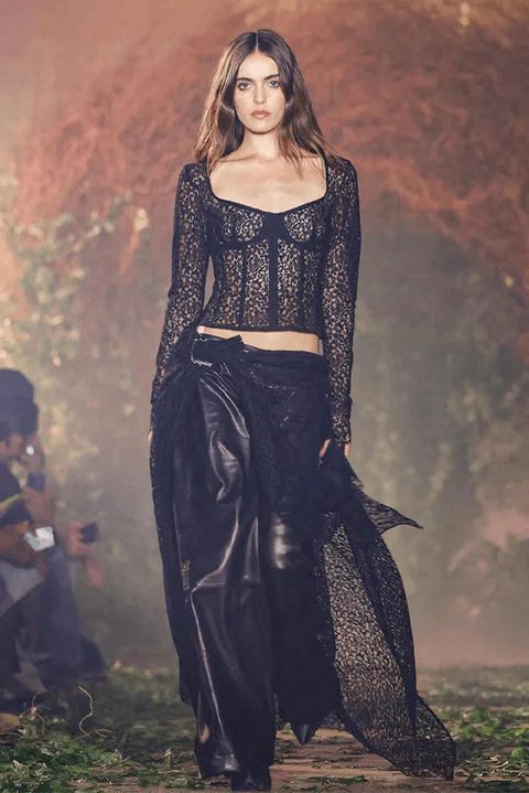 Femme défilant en tenue noire élégante lors d'un défilé de mode.