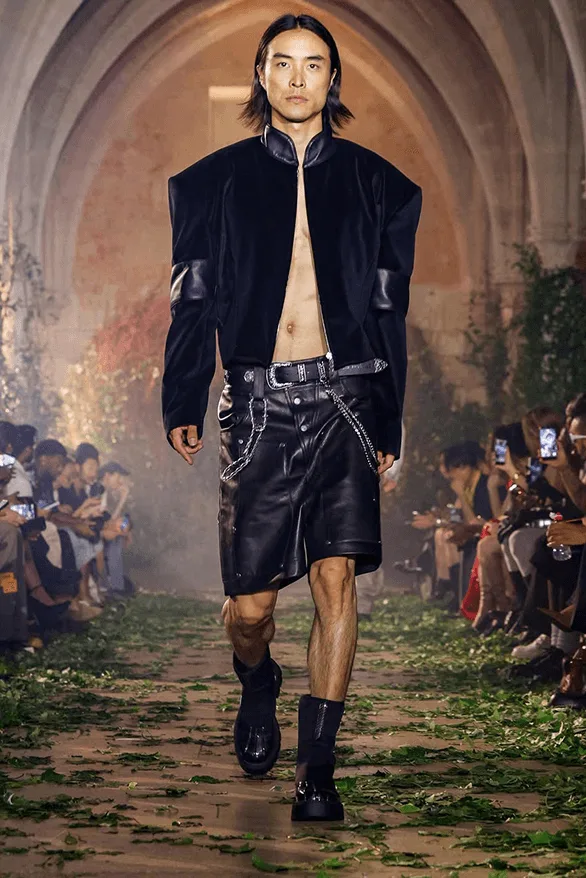 Homme défilant en veste et short en cuir noir.