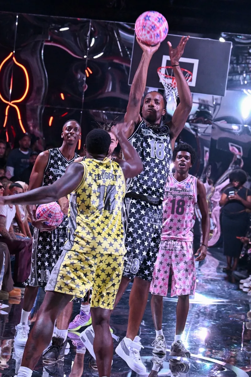 Homme tirant au basket sur terrain coloré avec joueurs étoilés.