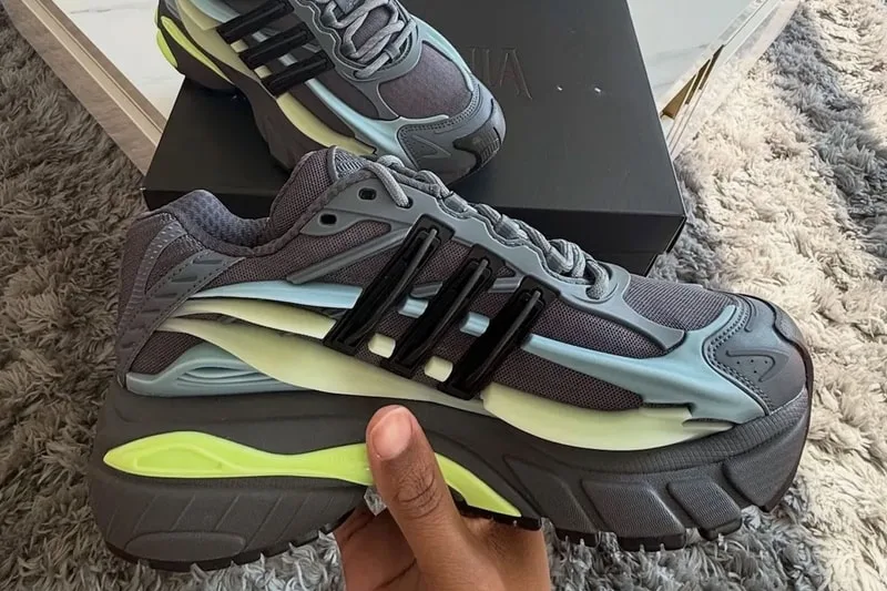 Chaussure de sport grise avec accents bleus et jaunes sur tapis gris