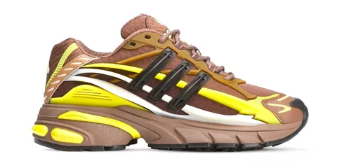 Chaussure de sport brune et jaune avec détails noirs et semelle épaisse.