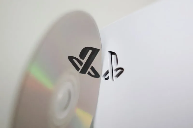 Logo PlayStation sur un disque avec une console en arrière-plan.