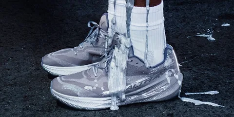 Chaussures de sport grises éclaboussées de liquide blanc sur le sol.