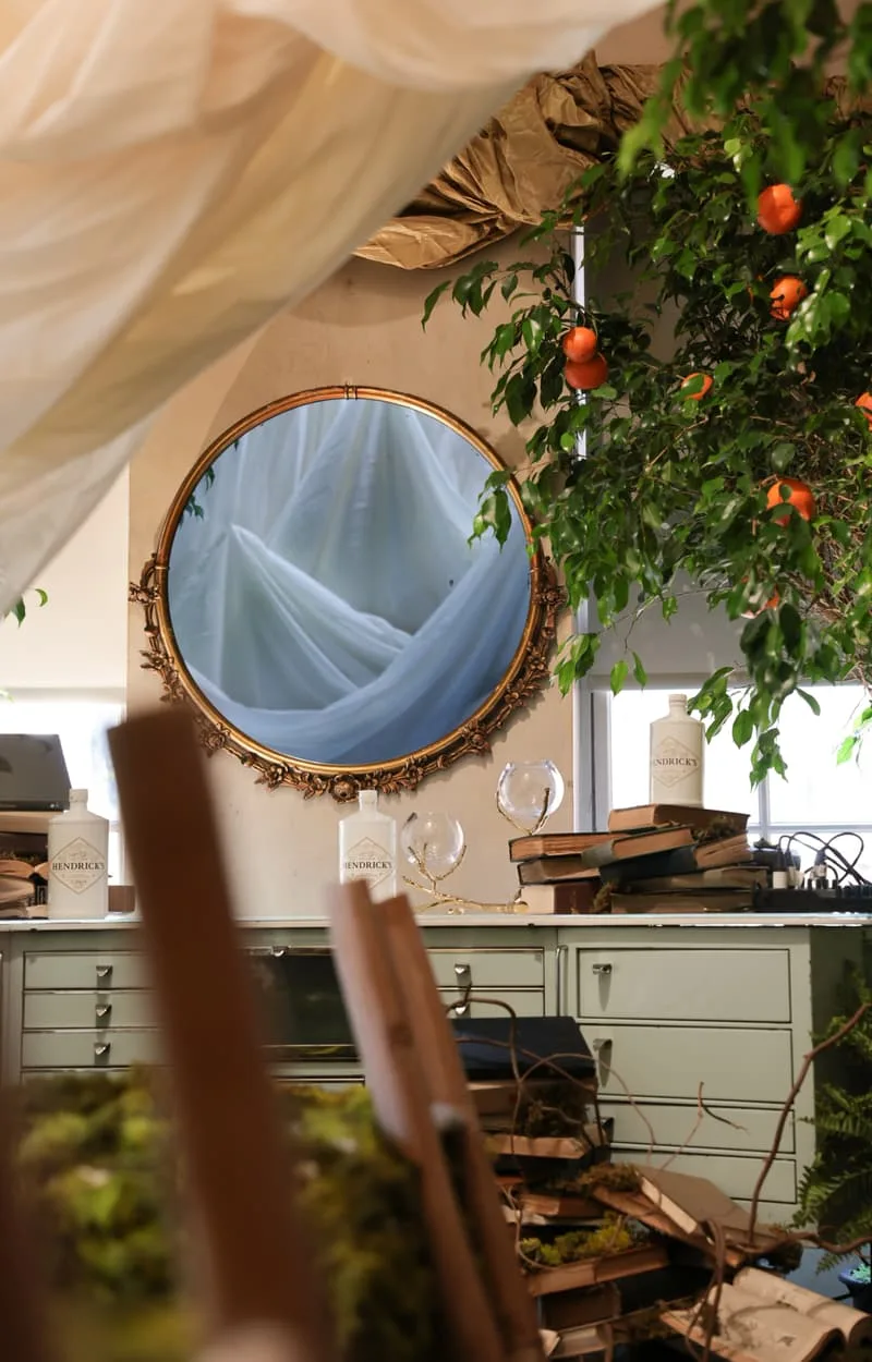 Miroir rond avec tissu bleu et arbre à fruits oranges dans une pièce décorée.