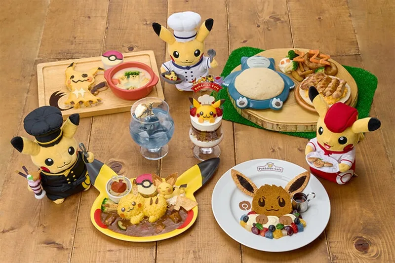 Peluches Pikachu chefs avec plats inspirés Pokémon sur table en bois.