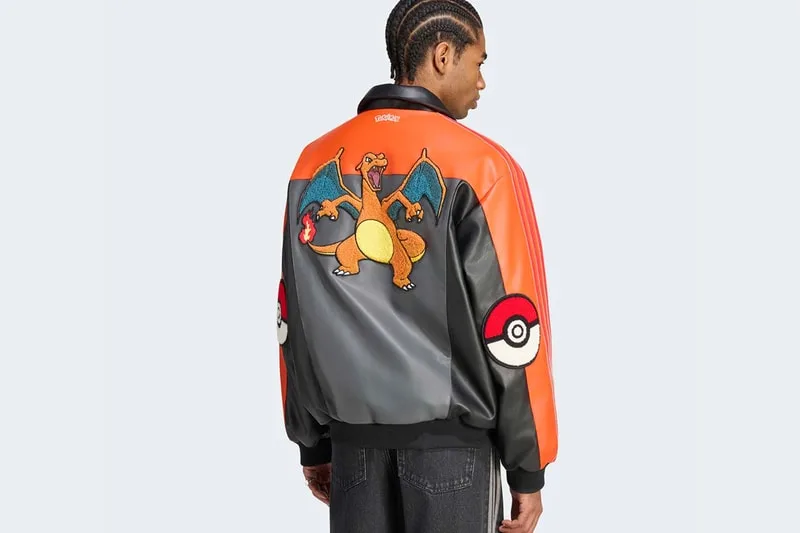 Homme avec veste Charizard colorée et logo Pokéball sur fond gris.