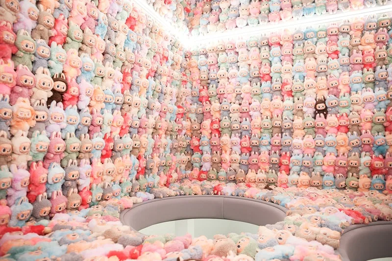 Salle avec murs tapissés de peluches colorées et siège au centre.