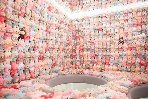 Salle avec murs tapissés de peluches colorées et siège au centre.