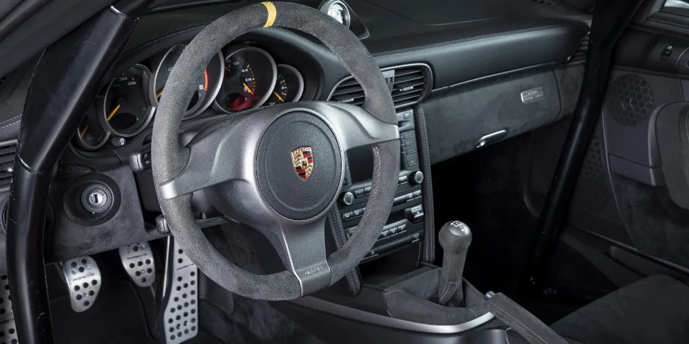 Intérieur d'une voiture Porsche avec volant et tableau de bord visibles.