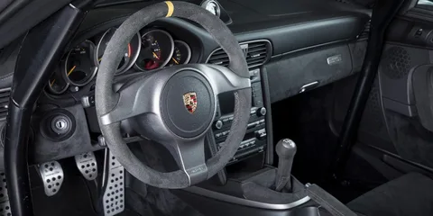 Intérieur d'une voiture Porsche avec volant et tableau de bord visibles.