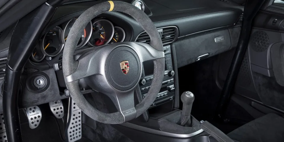Intérieur d'une voiture Porsche avec volant et tableau de bord visibles.