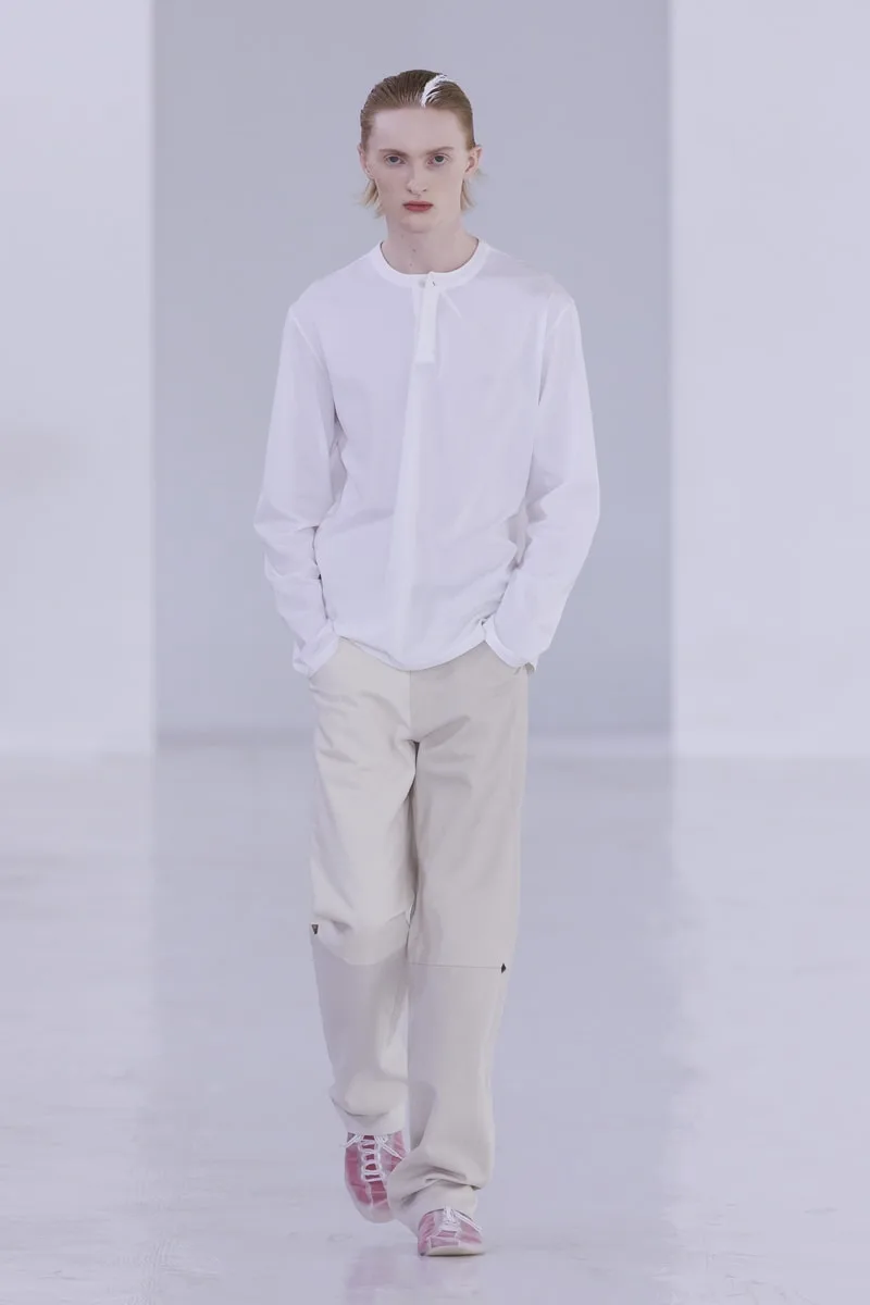 Défilé de mode homme avec tenue blanche et beige.