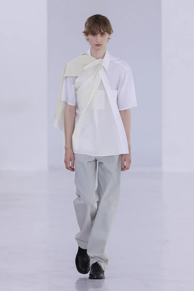 Homme en chemise blanche et pantalon clair sur un podium