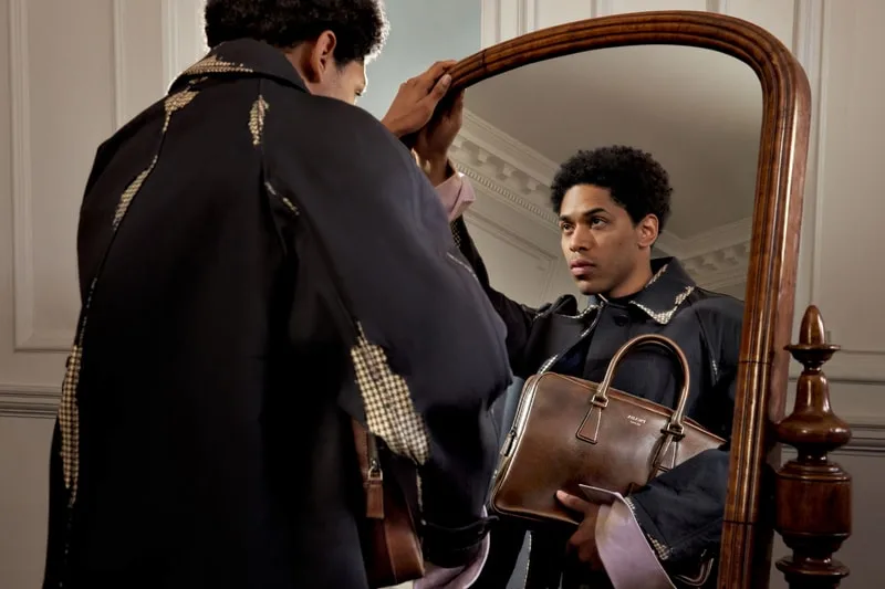 Homme devant un miroir tenant un sac de luxe.