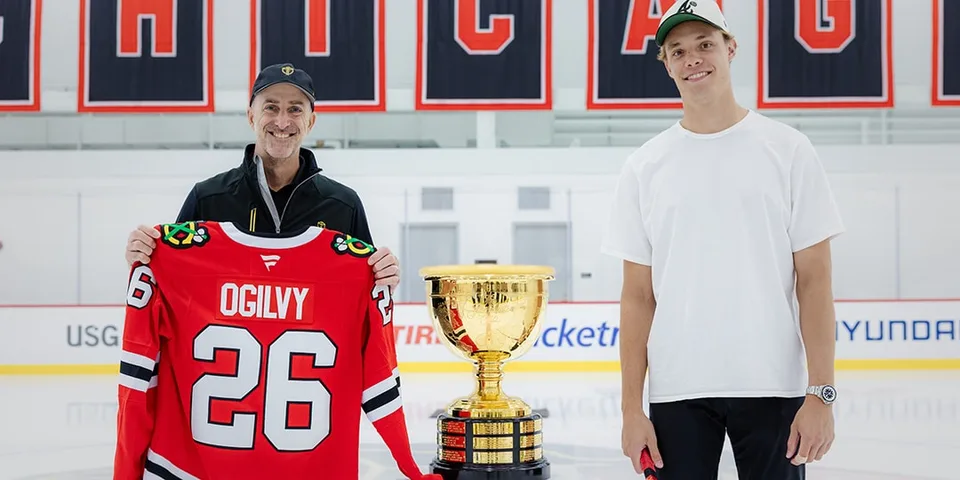 Deux hommes avec un maillot de hockey et un trophée sur la glace à Chicago.