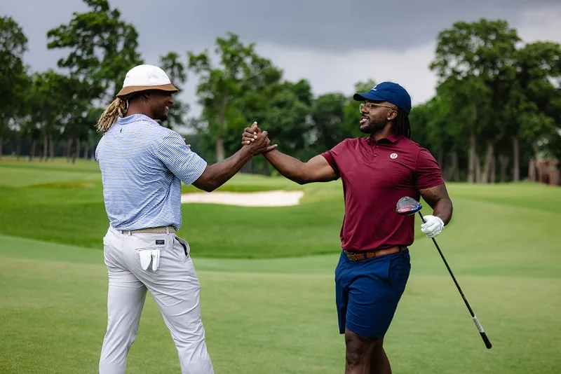 Deux hommes se serrent la main sur un terrain de golf.