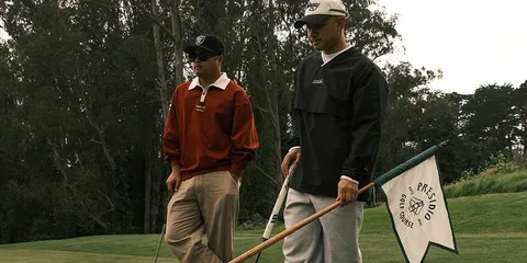 Deux hommes avec équipement de golf sur un parcours de golf.