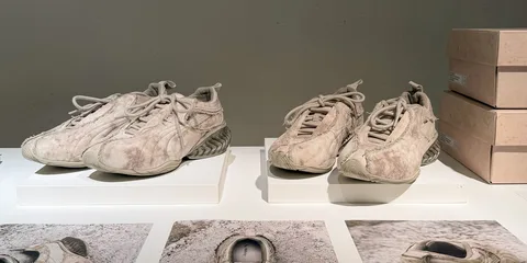 Paires de baskets beige usées exposées sur des socles blancs.