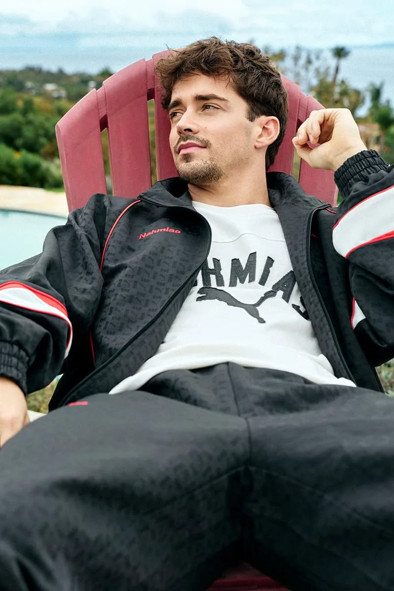 Homme en tenue de sport noire assis à l'extérieur sur une chaise rouge.