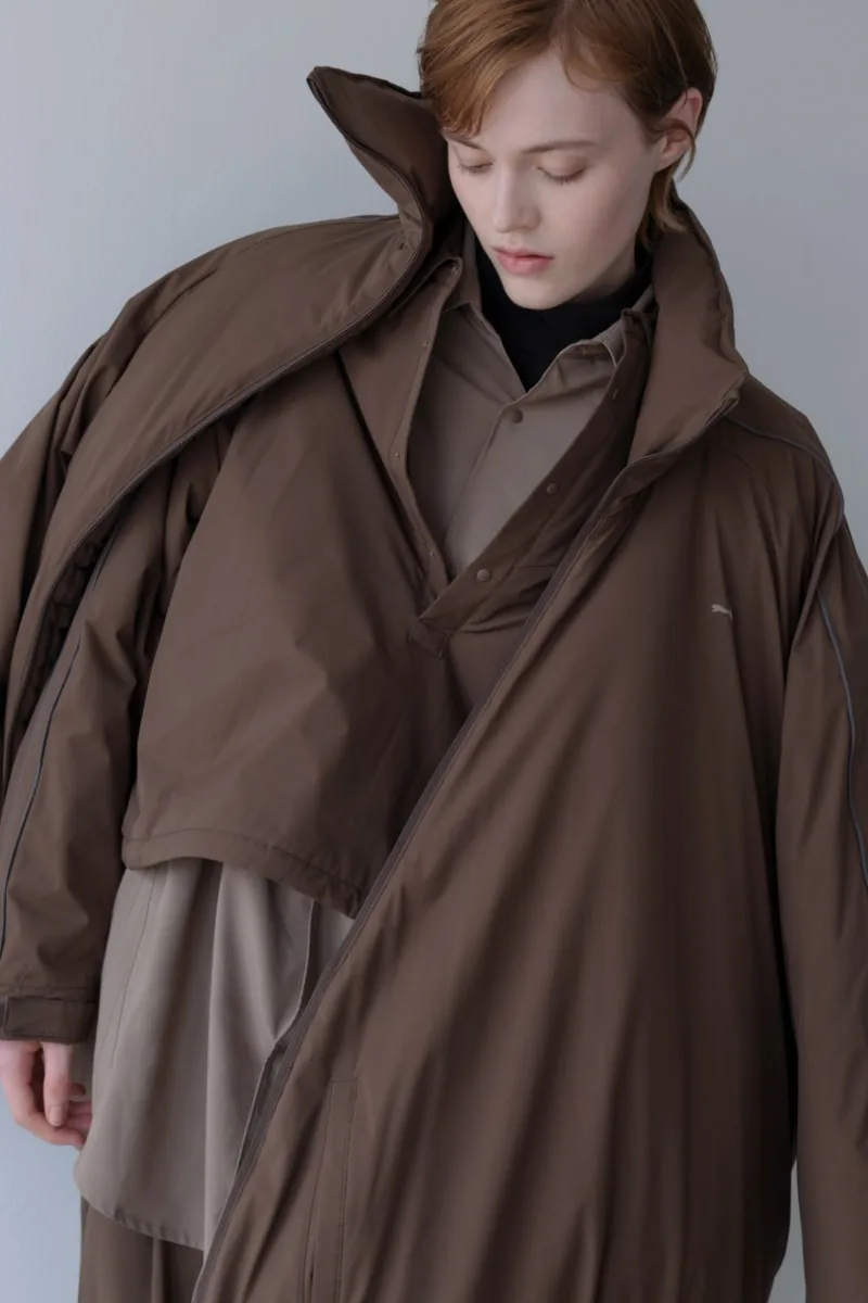 Personne vêtue de plusieurs couches de vêtements marron.