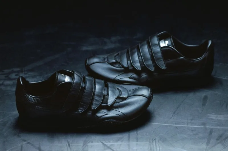 Chaussures en cuir noir avec bandes velcro sur fond sombre.