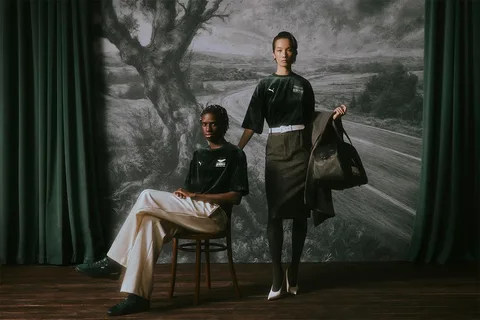 Deux mannequins posent devant un fond en noir et blanc avec des rideaux verts.