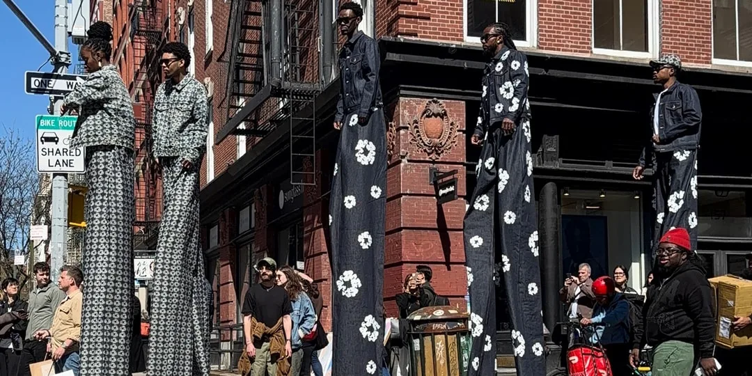 Des personnes sur échasses avec des vêtements à motifs floraux dans une rue.