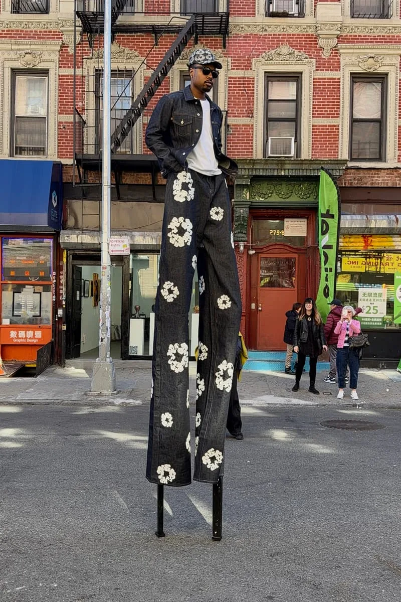 Homme sur échasses avec pantalon fleuri dans la rue.