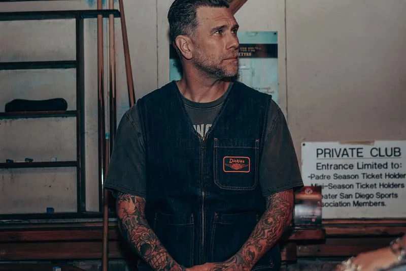 Homme tatoué en gilet en jean, dans un club privé.