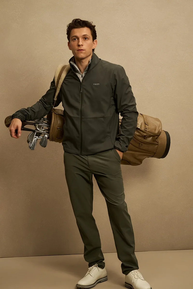 Homme posant avec sac de golf, veste et pantalon kaki.