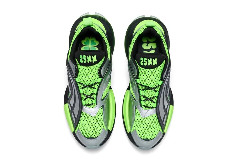 Paire de baskets vertes et noires avec motif trèfle sur la semelle intérieure.
