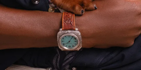 Montre-bracelet turquoise sur poignet avec bracelet en cuir marron.