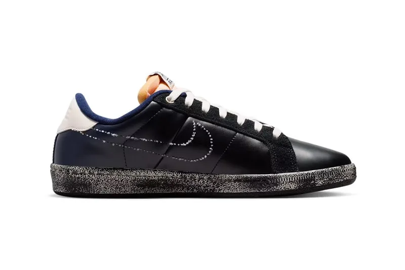 Chaussure noire avec semelle mouchetée et logo sur le côté.