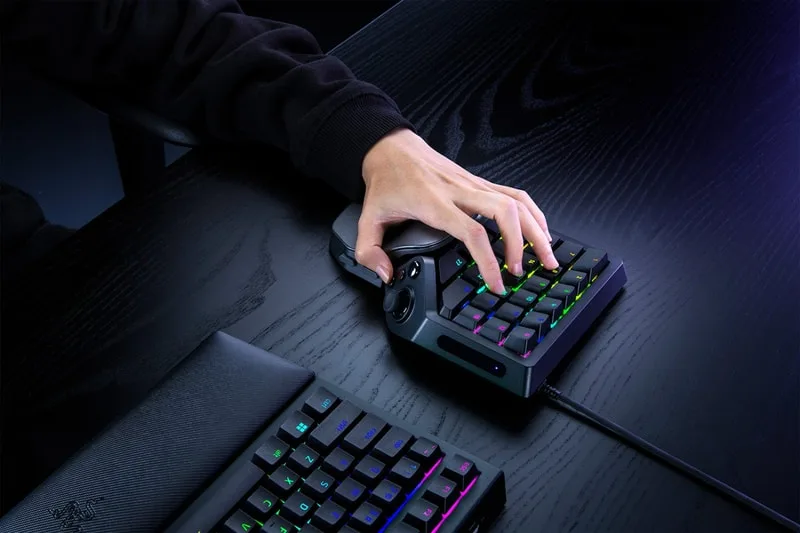 Personne utilisant un clavier de jeu rétroéclairé sur un bureau.