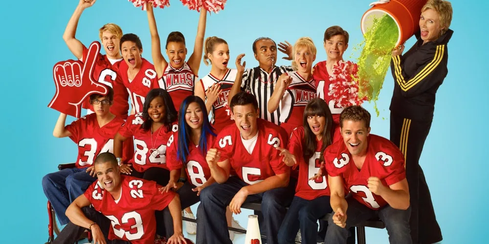 Équipe de football américain en rouge pose avec des pom-pom girls et un seau de peinture.