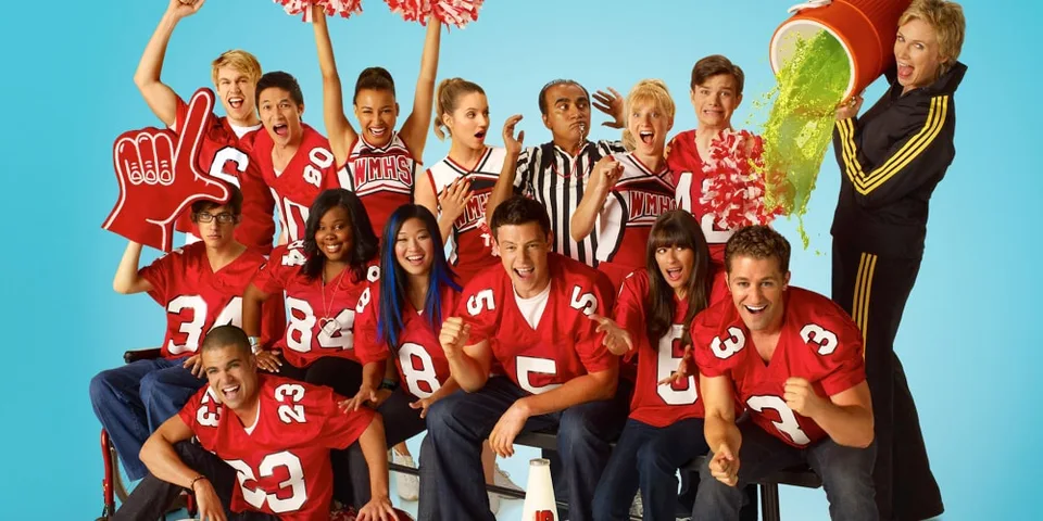 Équipe de football américain en rouge pose avec des pom-pom girls et un seau de peinture.