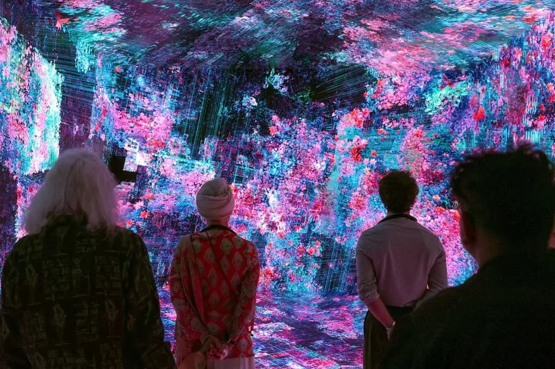 Personnes devant une installation artistique numérique lumineuse et colorée.