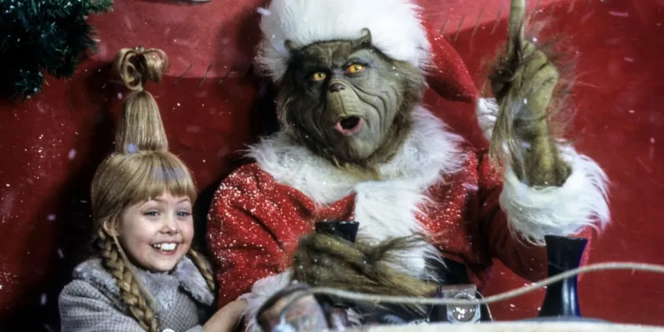 Le Grinch et une fille heureuse dans un traîneau de Noël.