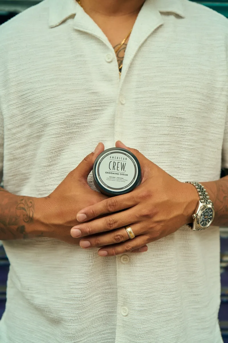 Homme en chemise tenant un produit entre les mains, montre-bracelet visible.