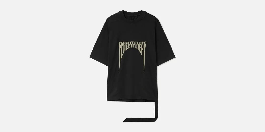 T-shirt noir ample avec imprimé graphique beige et longue bande de tissu pendante.