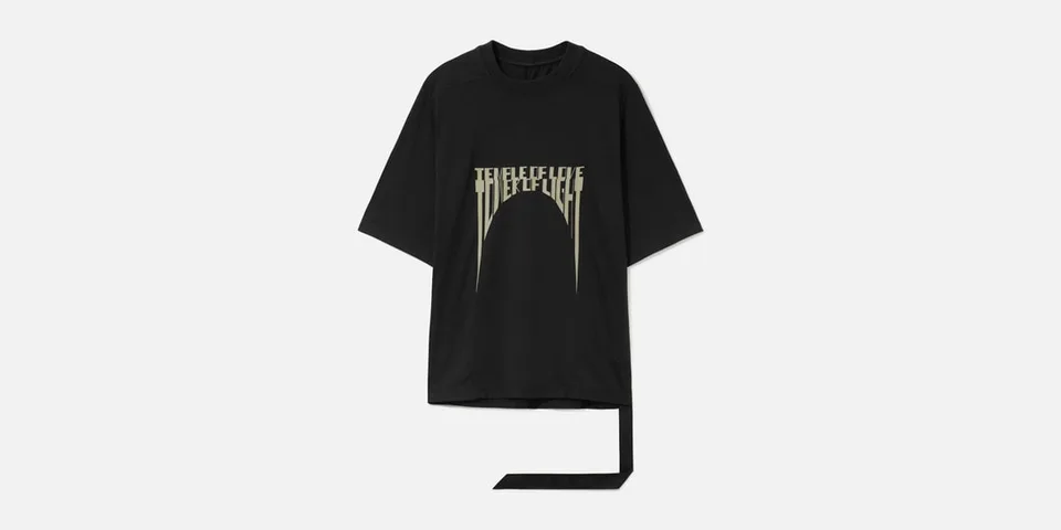 T-shirt noir ample avec imprimé graphique beige et longue bande de tissu pendante.