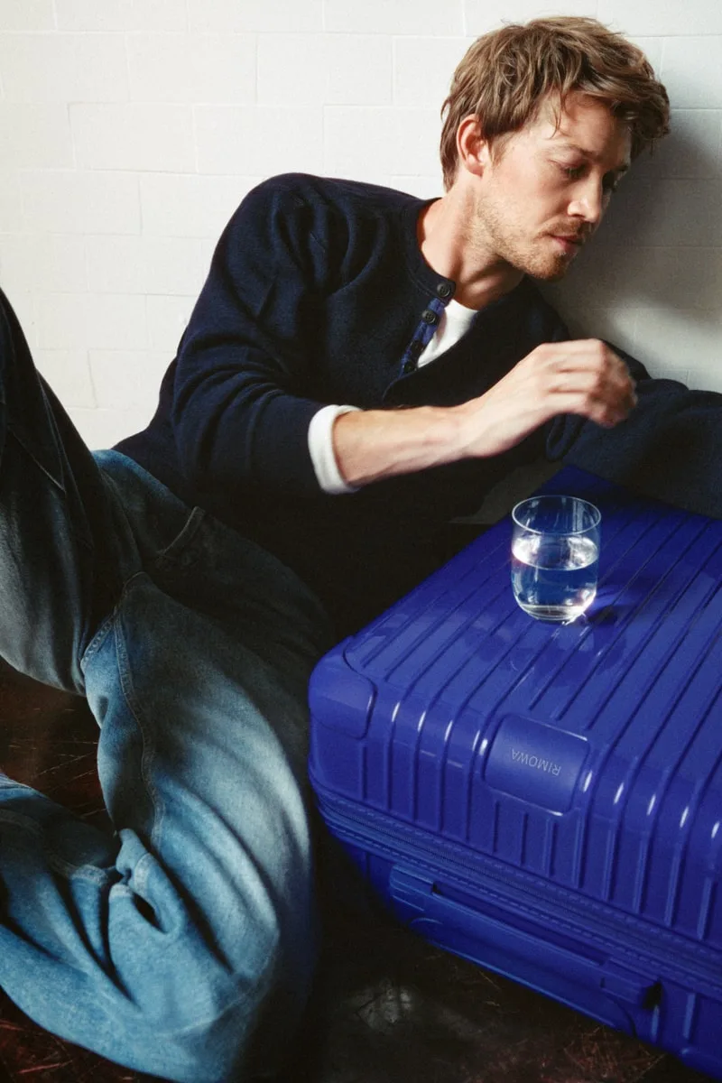 Homme assis avec valise bleue et verre d'eau
