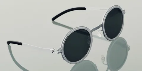 Lunettes de soleil rondes à monture argentée posées sur une surface réfléchissante.